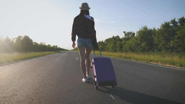 Traveler woman with suitcase on road to travel. Concept of travel.