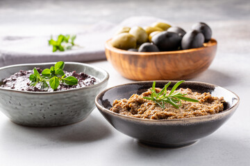 Tapenade - paste made from olives. Bowls with spreadable black and green olive cream on concrete...