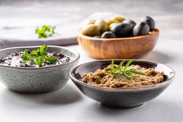 Gordijnen Tapenade - paste made from olives. Bowls with spreadable black and green olive cream on concrete background. © geshas