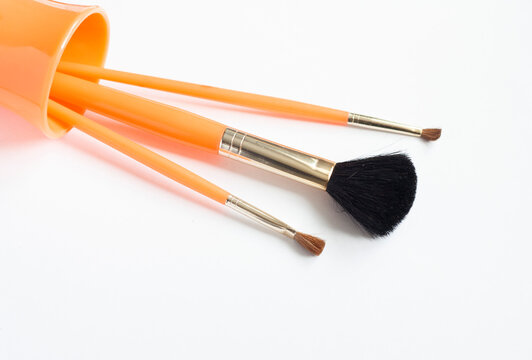 Orange Makeup Brushes In A Glass On A White Background