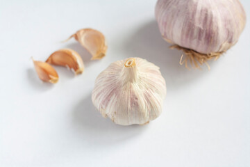 Two garlic heads and three cloves on a white background