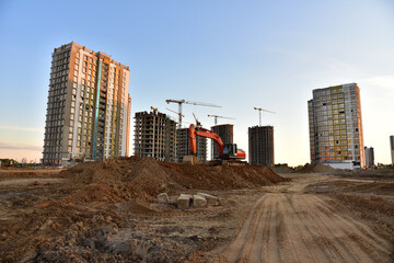 Excavator on earthmoving at construction site. Road work and Dig pit foundation. Tower cranes in...