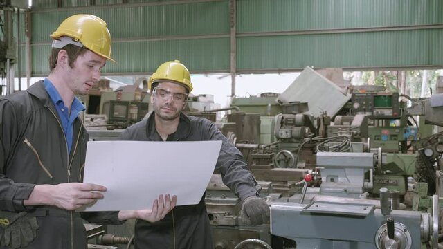 Team engineer working looking report on blueprint, two man planning project, technician inspect and fix machine, entrepreneur management and control in factory, industrial and construction concept.