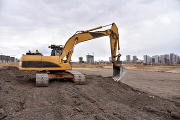 Fototapeta na wymiar Excavator working at construction site on groundwork. Backhoe digs gravel and concrete crushing. Recycling old concrete from demolition at a landfill for the disposal of construction waste