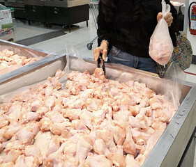 Buying fresh chicken wings arranged on a tray.