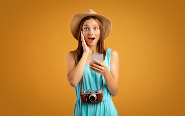 Shocked girl traveller with smartphone on yellow