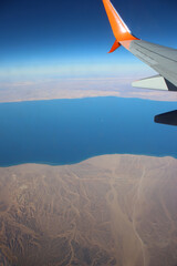 Photo from the plane window. Red sea and desert landscape. From high. Under the wing of an airplane