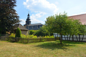Fototapeta na wymiar Village view traditional buildings with garden, trees, wooden fence and the church