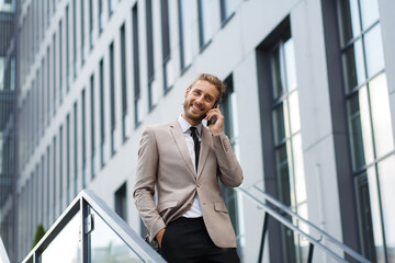 Portrait of a successful young businessman. A curly-haired man in a white shirt with a telephone against the background of a modern business center.