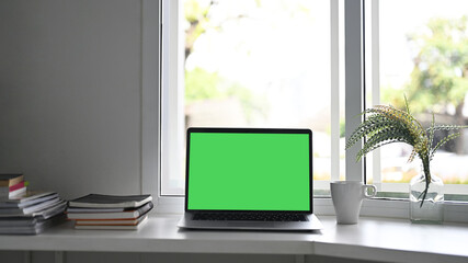 Workspace laptop computer with green screen and office supplies.