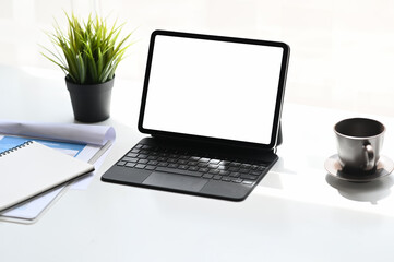 Office desk with mock up tablet with blank sccreen, supplies and decorations on white table.