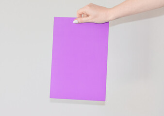  Blank colored sheet of cardboard in a womans hand on a white background with text space. A sheet for announcing and informing people. Information plate