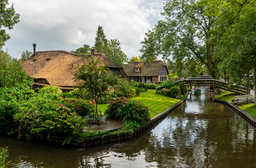 Fototapeta na wymiar Giethoorn, The Netherlands - August 28, 2020: View over thatched roof houses and a boat on the canal