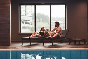 Couple enjoying their spa center vacation, relaxing by the swimming pool