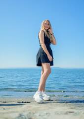 Woman in dress enjoys a walking near the sea shore.