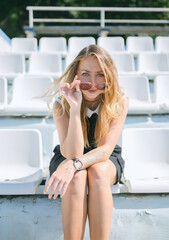 Young woman is sitting on a stadium chair alone.