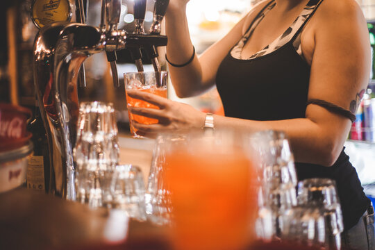 Dettaglio immagine mani di una barista che versa una bevanda nel bicchiere durante il lavoro in un bar notturno