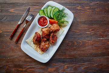 Shashlik, meat cooked on skewers on an open table, in a white plate on a wooden background