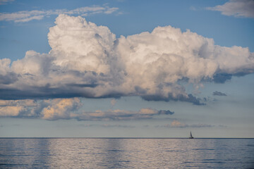 Naklejka na ściany i meble Beeindruckende Wolken über dem Meer. Am Horizont ein kleines Segelboot