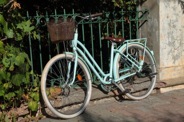 Fototapeta na wymiar Green retro bike standing in front of the fence
