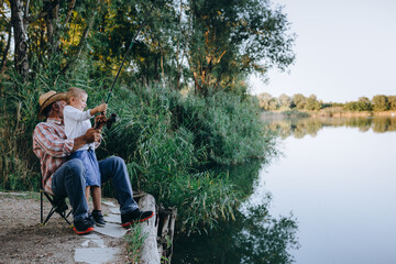 grandfather and grandson fishing outdoor on the lake, little boy looking at the camera