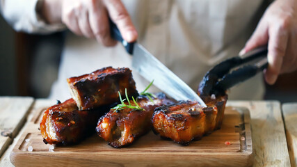 Selective focus. BBQ blue ribs. Chef with a knife cuts barbecue ribs on the board.