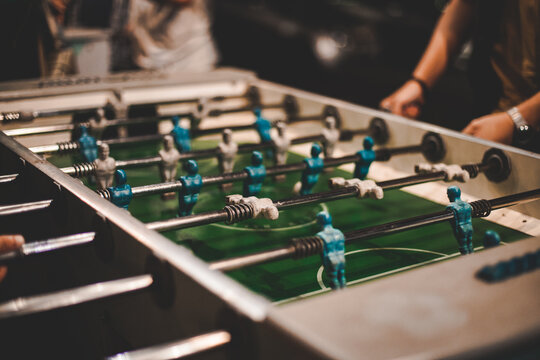 Dettaglio mani di ragazzi in un momento di gioco serale a calcio balilla in un locale serale