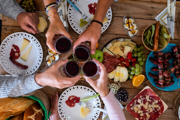 Family friends have fun together in winter eating food on a wooden table - vertical top view and concept of friendship and caucasian people enjoying celebration at home or restaurant