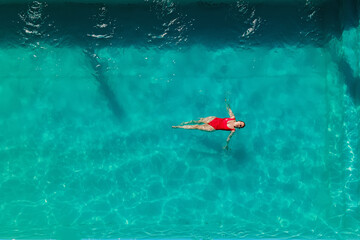 Fototapeta premium Woman in red bikini are swimming in the pool with turquoise water