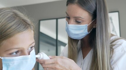Kid at doctor's office with protection face mask having temperature checked - Powered by Adobe