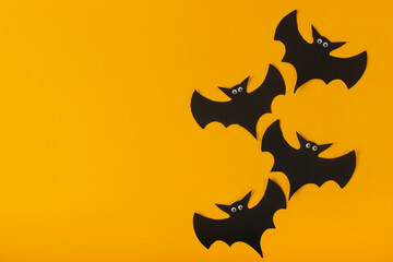 Black bats with eyes on a yellow background. Copy space.
