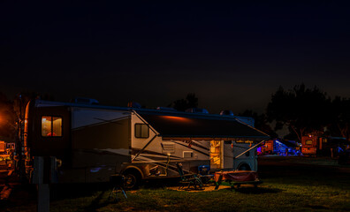 Camping in a motorhome in a Rv resort park in the evening with lights on Rv's around the park
