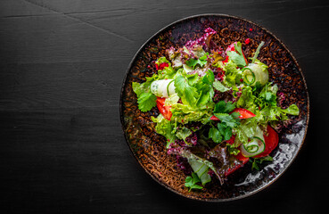 various fresh mix salad leaves with tomato, cucumber and red pepper on a plate