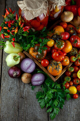 Tomatoes, peppers, onions on the table. Preservation of the autumn harvest of vegetables. Glass jar with pickled tomatoes. Wooden background. Vegetable food. Still life. Tomato of different varieties.