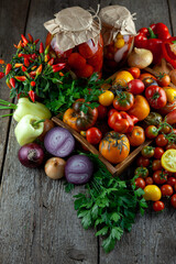 Tomatoes, peppers, onions on the table. Preservation of the autumn harvest of vegetables. Glass jar with pickled tomatoes. Wooden background. Vegetable food. Still life. Tomato of different varieties.