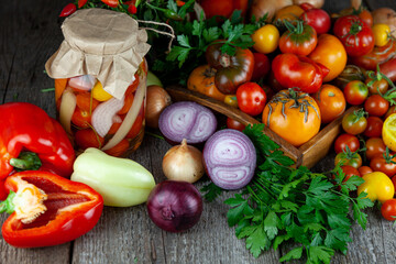 Tomatoes, peppers, onions on the table. Preservation of the autumn harvest of vegetables. Glass jar with pickled tomatoes. Wooden background. Vegetable food. Still life. Tomato of different varieties.