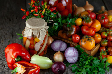 Tomatoes, peppers, onions on the table. Preservation of the autumn harvest of vegetables. Glass jar with pickled tomatoes. Wooden background. Vegetable food. Still life. Tomato of different varieties.