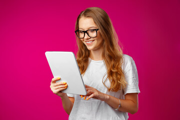 Attractive young woman using digital tablet against pink background