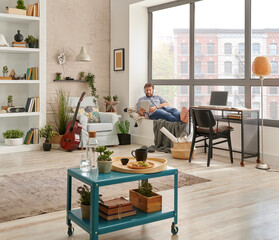 Man in the room and listening to the music with laptop style, decorative living room corner and view.