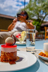 Dessert and Woman Using Phone in a Sunny Day in an Outdoor Restaurant.