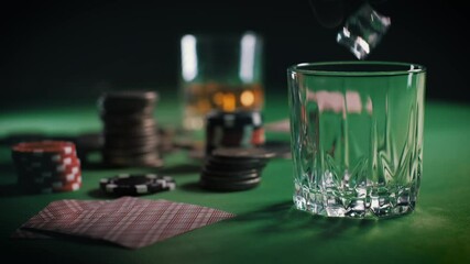 Cubes of ice slowly fall into the glass and then the whiskey or rum is poured. Casino Poker Chips, Coins And Deck Of Playing Cards Stacked In Multiple Piles On Table. Gambling fortune. Slow motion - Powered by Adobe
