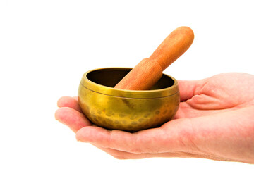 Hand holding a small Tibetan singing bowl made from brass.