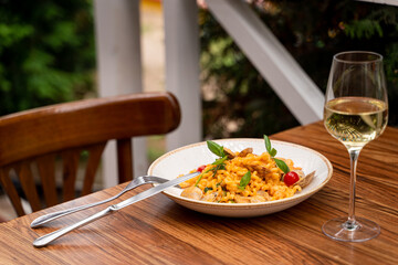 Restaurant terrace with wooden table: seafood pasta with mussels and a glass of a good white wine