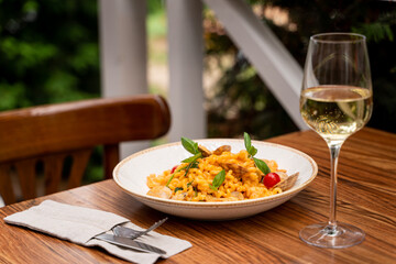 Restaurant terrace with wooden table: seafood pasta with mussels and a glass of a good white wine
