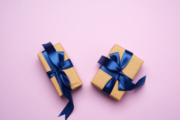 rectangular box wrapped in brown paper and tied with a blue silk ribbon with a bow