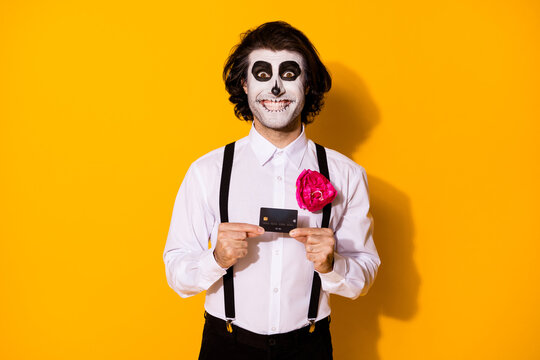 Portrait of his he nice handsome spooky cheerful cheery glad lucky guy holding in hands plastic card money transfer deposit calavera sale isolated bright vivid shine vibrant yellow color background