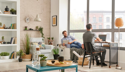 Two man friends in the room and working together. Listening to the music and modern decoration style.