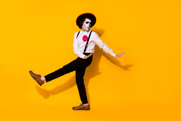 Fototapeta na wymiar Photo of spooky ghost guy dance spanish latin dance carefree festival hands eyes closed wear white shirt death costume sugar skull suspenders pants shoes isolated yellow color background