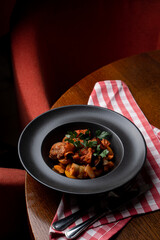 Top view from the distance of pork and potato stew in a dark posh restaurant