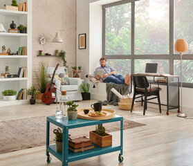 Man in the room, corner interior style, listening to the music with laptop and working from home. Modern decoration style.